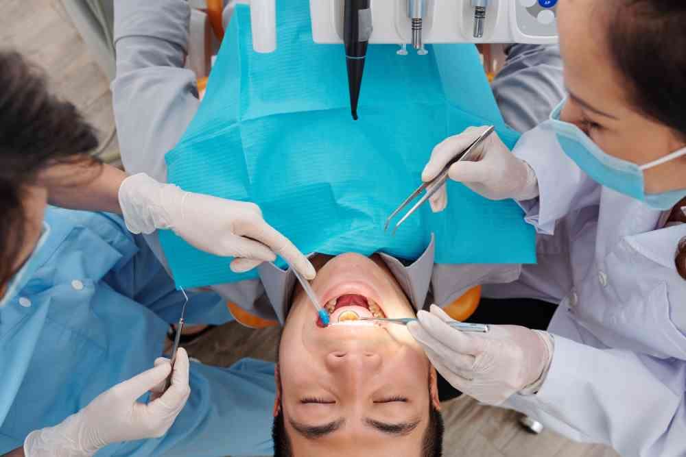 Patient sitting in dental chair with his mouth wide open when dentist checking teeth and looking for cavity, gum disease and plaque